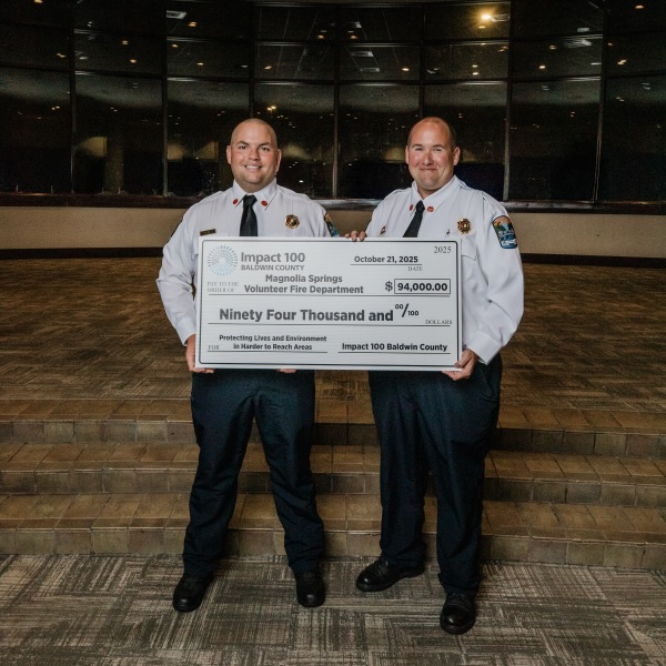 Smiling women holding a large check