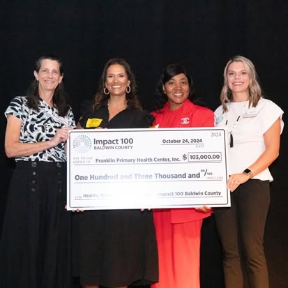 Smiling women holding a large check